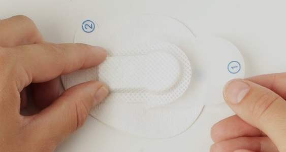Pulling down the bottom foil and pressing the patch around the sensor